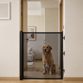 Puerta retráctil negra MotaCero Guard instalada en un paso interior, con un perro detrás de la malla.